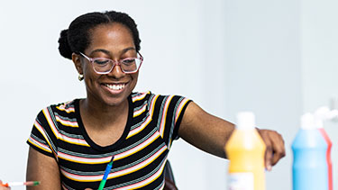 Student teacher with bottles of craft paint