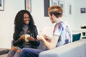 Students talking with hot drinks in accommodation